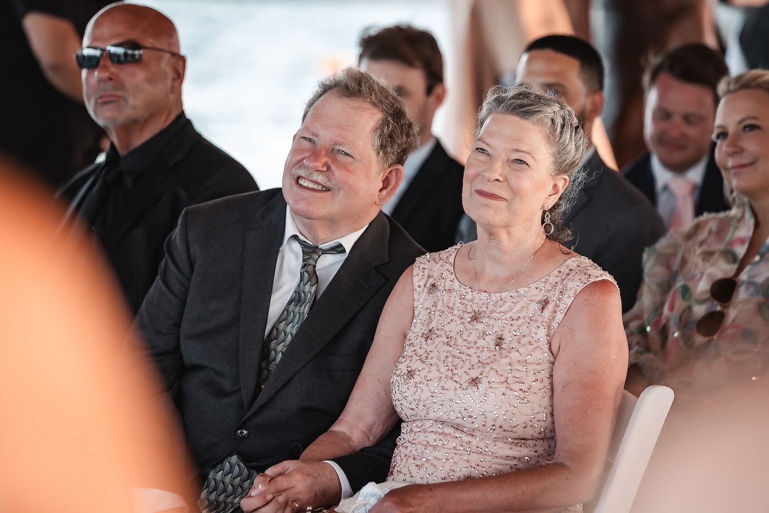 Wedding guests enjoying ceremony in outdoor venue with natural lighting.