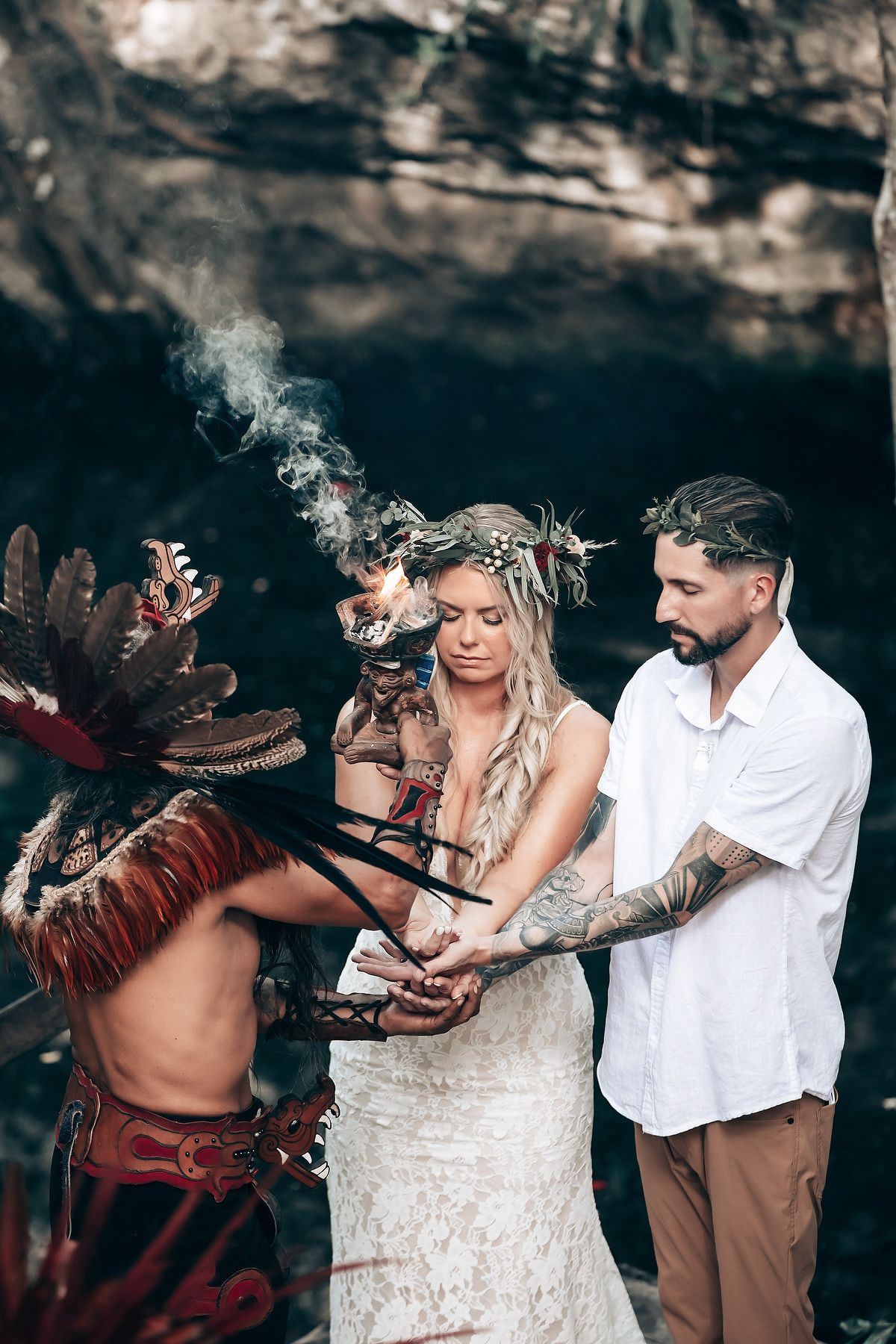 Traditional blessing ceremony in a cave setting with ceremonial performers in feathered headdresses.