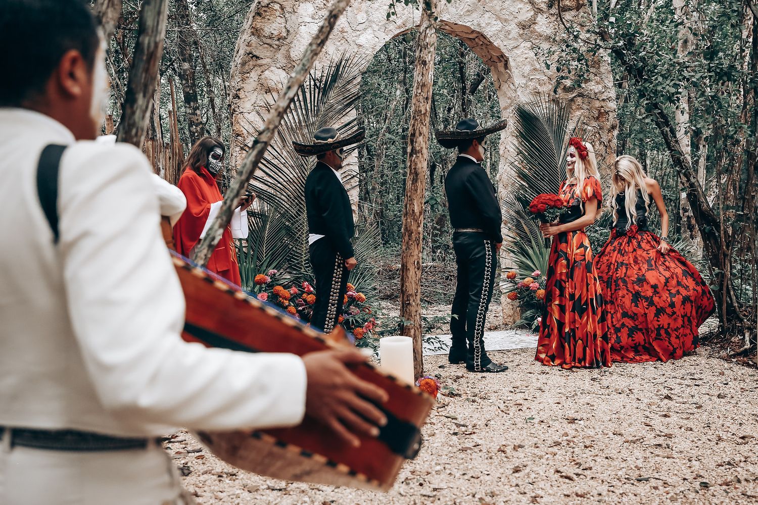 Gothic wedding ceremony in progress under stone archway with red decorative elements.