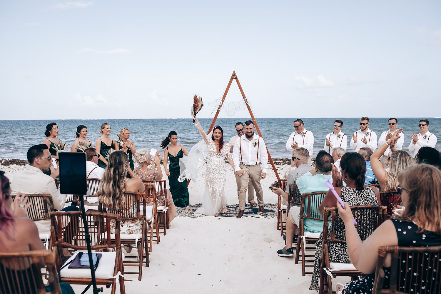 Beach wedding ceremony setup with wooden chairs and decorations along the oceanfront.