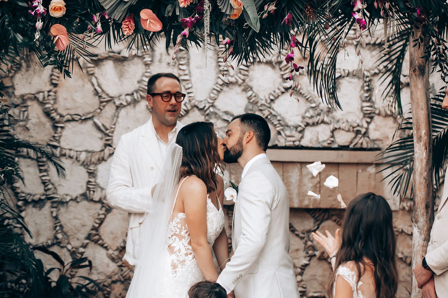 Wedding celebration in a tropical garden venue with stone walls and palm trees.