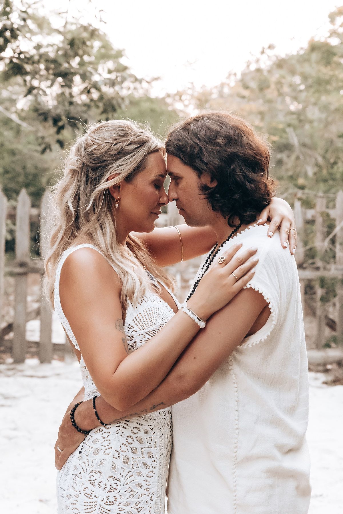 A romantic outdoor wedding photo series showing tender moments between two people in white attire among trees.
