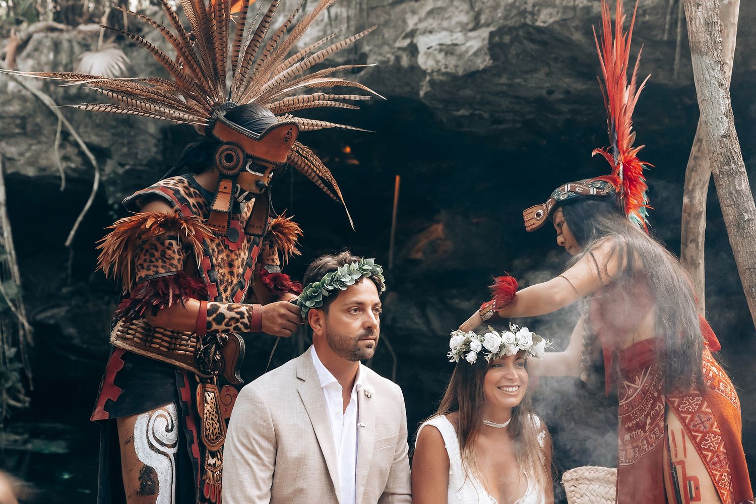 A traditional Mayan wedding ceremony takes place in a lush jungle setting with ceremonial headdresses and decorations.