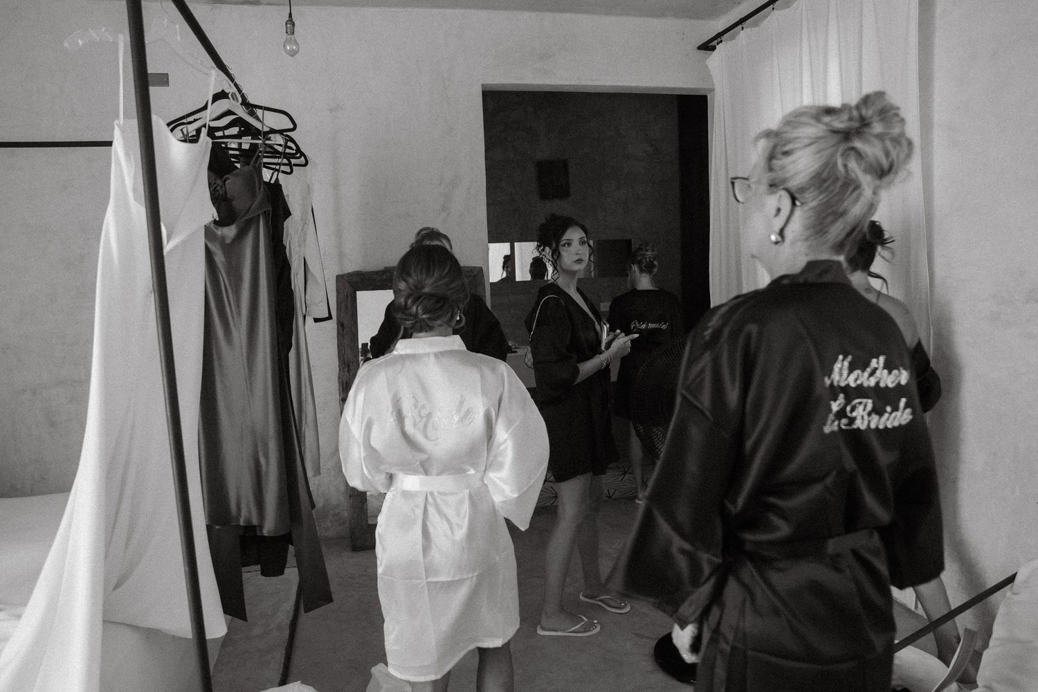 Black and white photo of bridal party getting ready with Mother of the Bride robe visible.