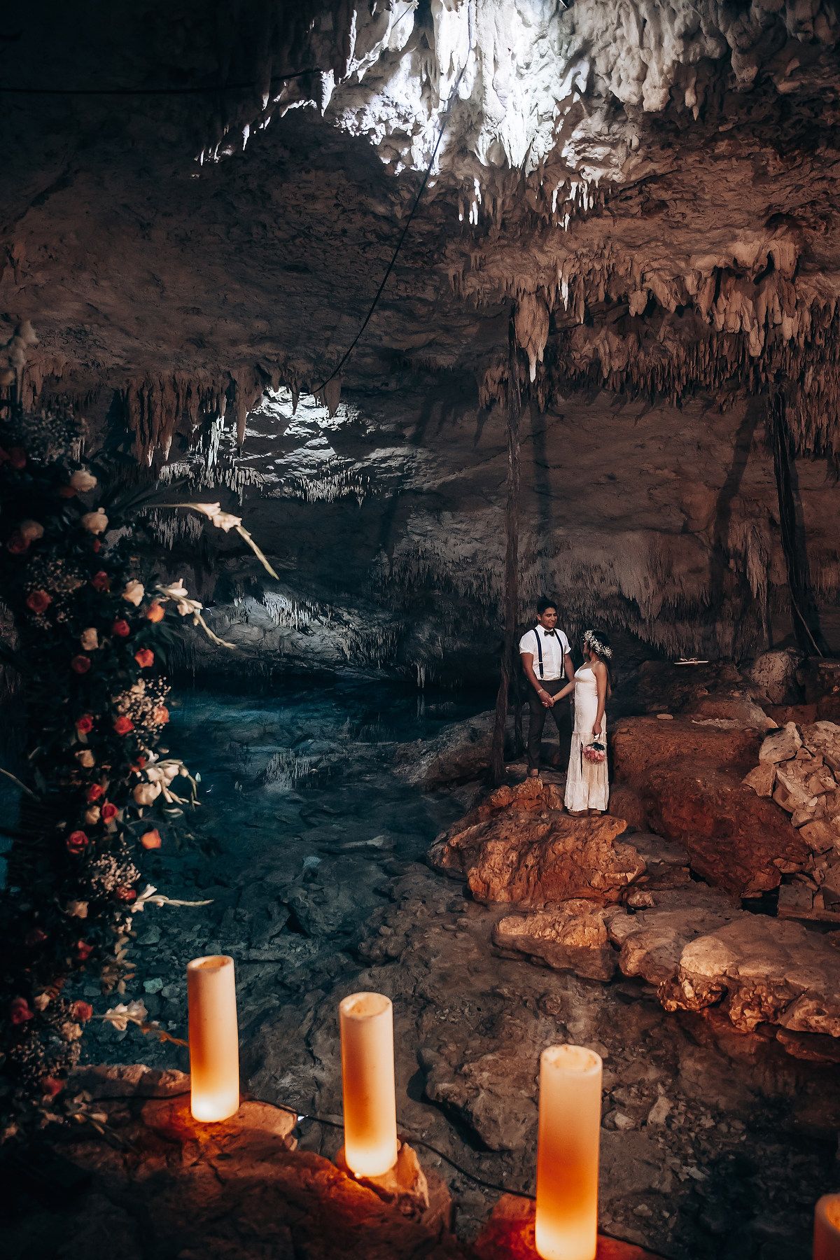 Romantic cave setting with glowing candles illuminating stalactites and rock formations in warm amber light.
