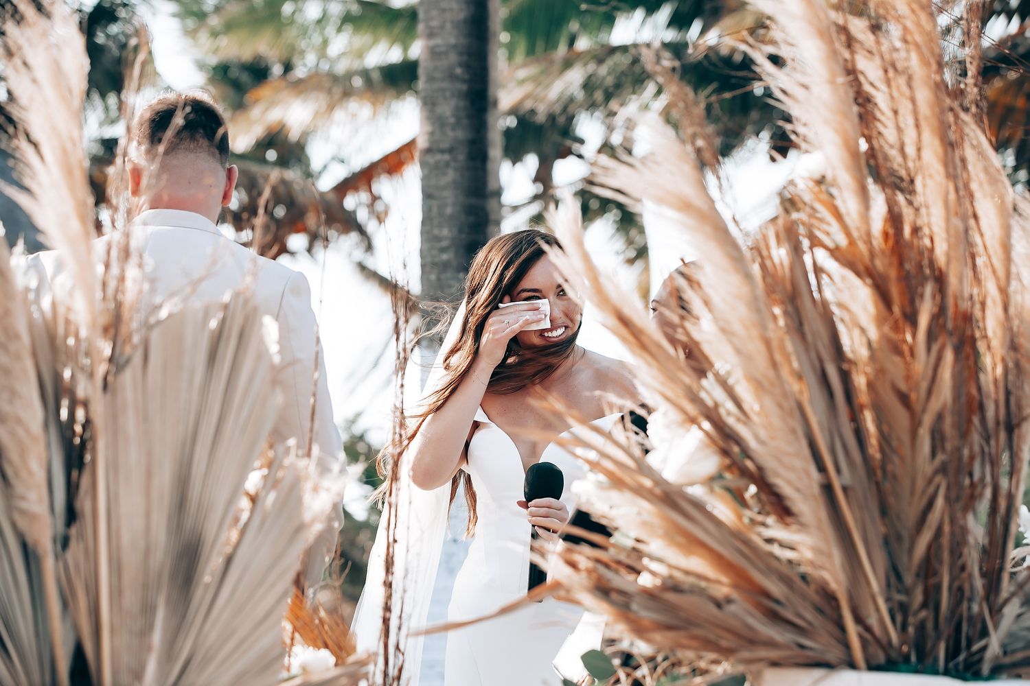 Dried pampas grass and palm fronds arranged in neutral tones create an elegant bohemian wedding ceremony backdrop.