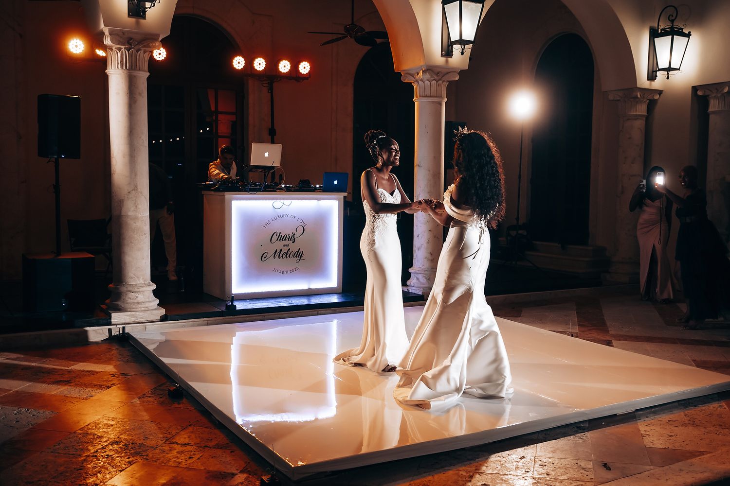 Wedding dance floor illuminated by warm lighting and arched architectural details.