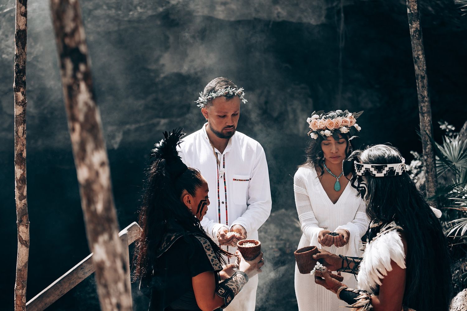 A spiritual ceremony unfolds in a wooded setting with participants wearing white clothing.