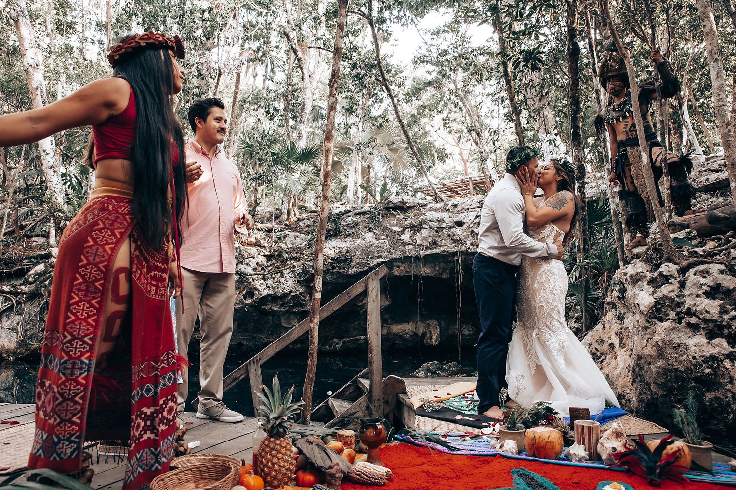 An intimate forest wedding ceremony with red decorative elements and natural woodland backdrop.