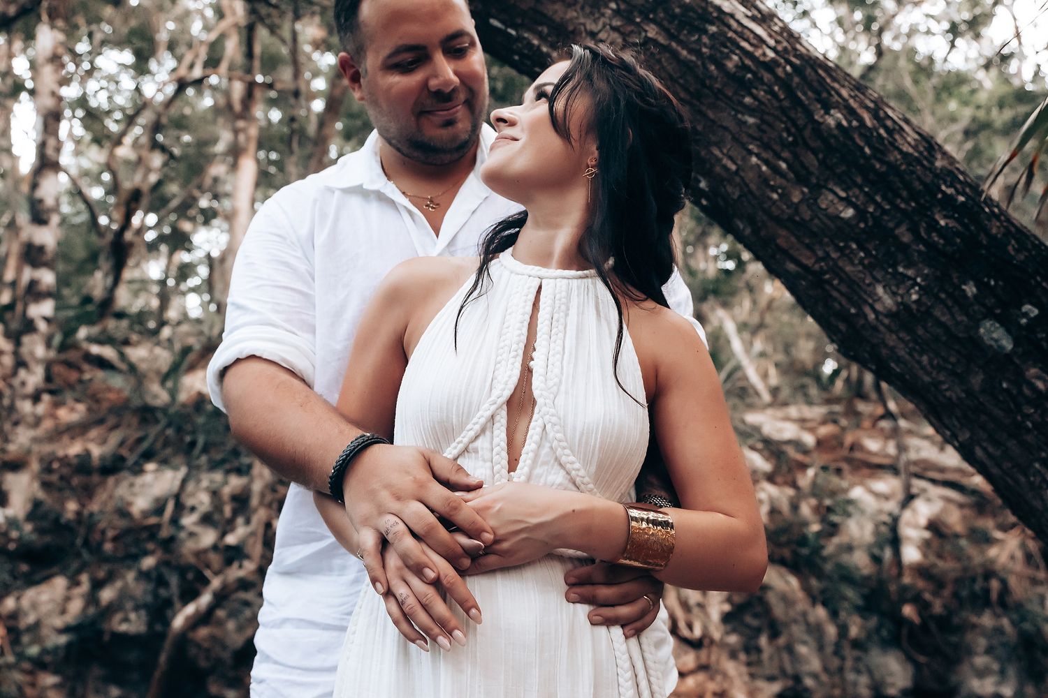 Romantic couple sharing tender moment during outdoor forest wedding photoshoot.