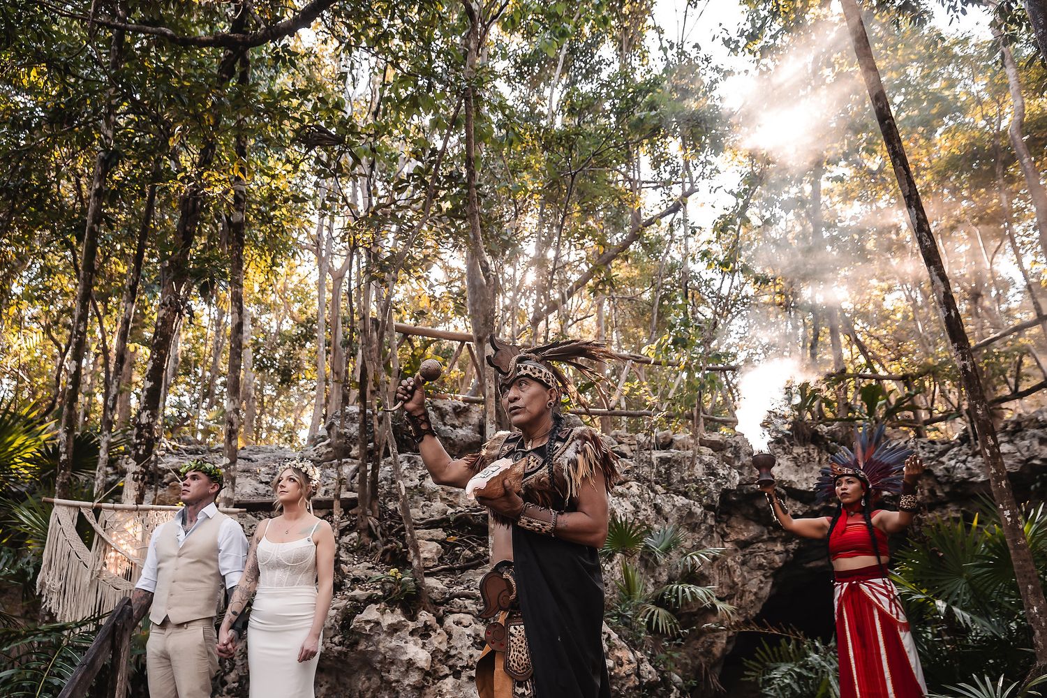Mayan ceremony in a lush jungle with performers in traditional attire blessing a couple near ancient ruins.