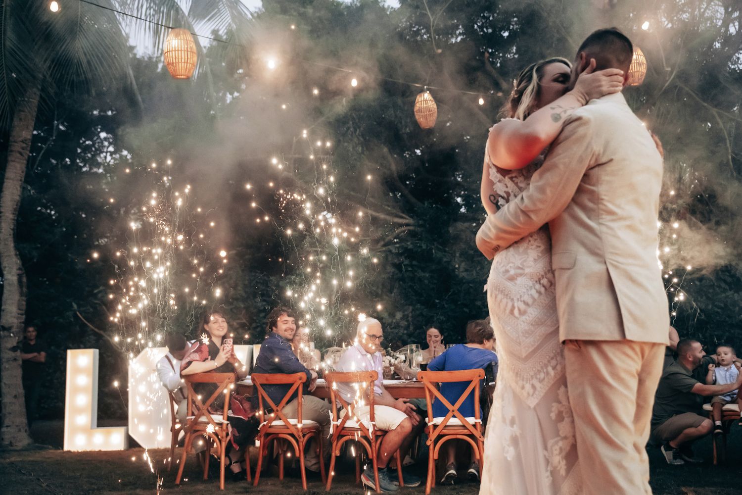 Couple dancing surrounded by sparkling fireworks display at romantic outdoor wedding reception.