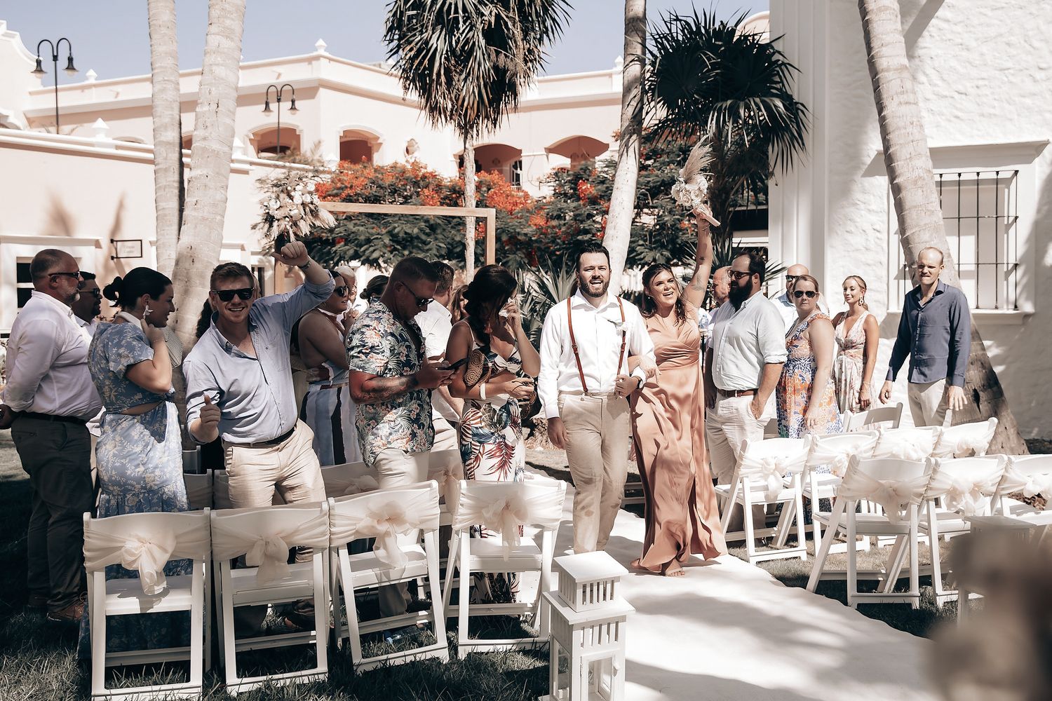 A couple celebrates their wedding with friends and family in an outdoor setting.