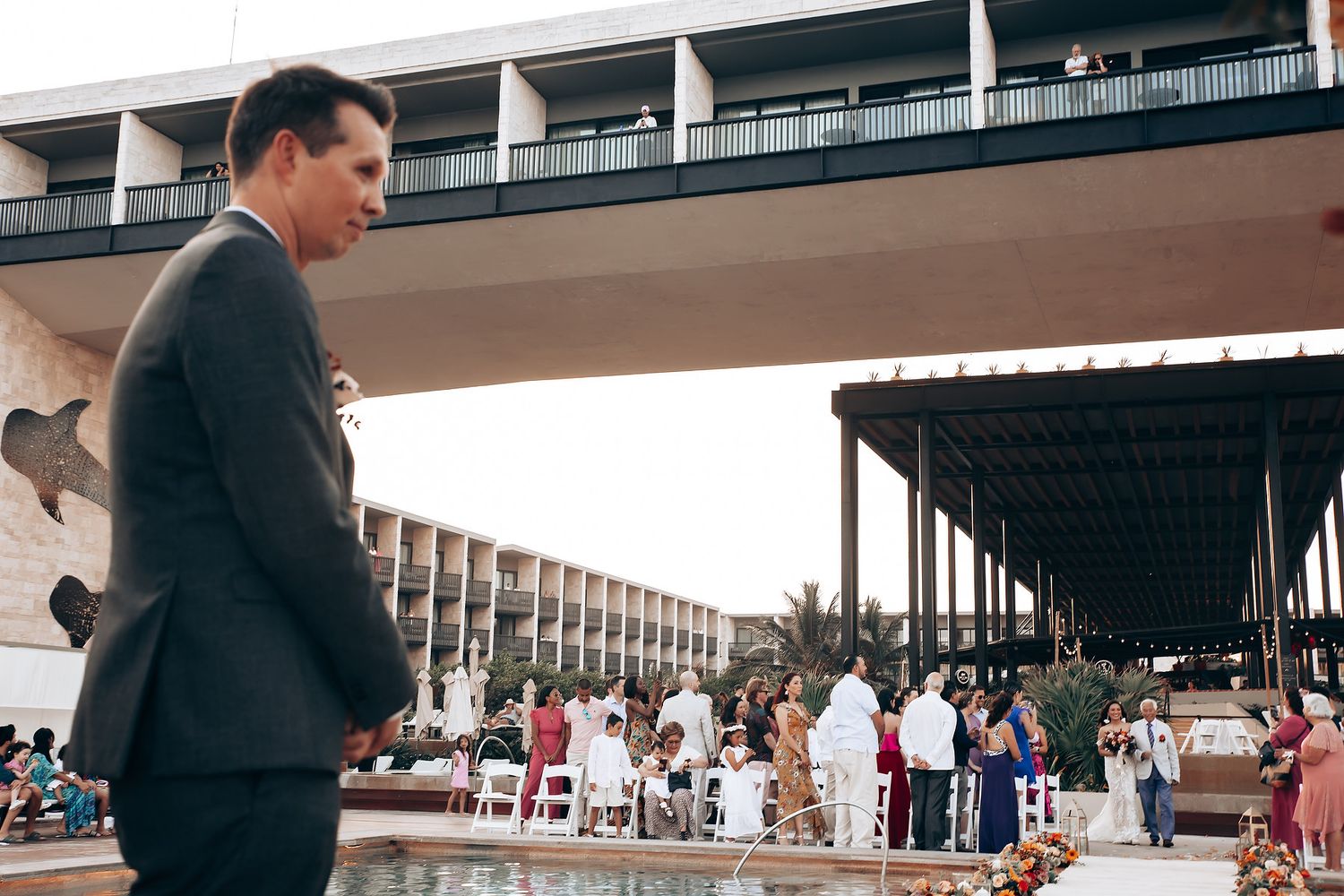 Guests gather around a poolside venue at an elegant outdoor event.