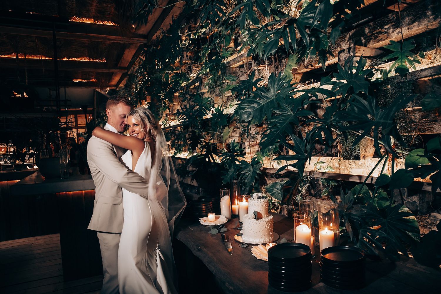 Romantic evening reception setting with hanging greenery and candlelight creating intimate ambiance.