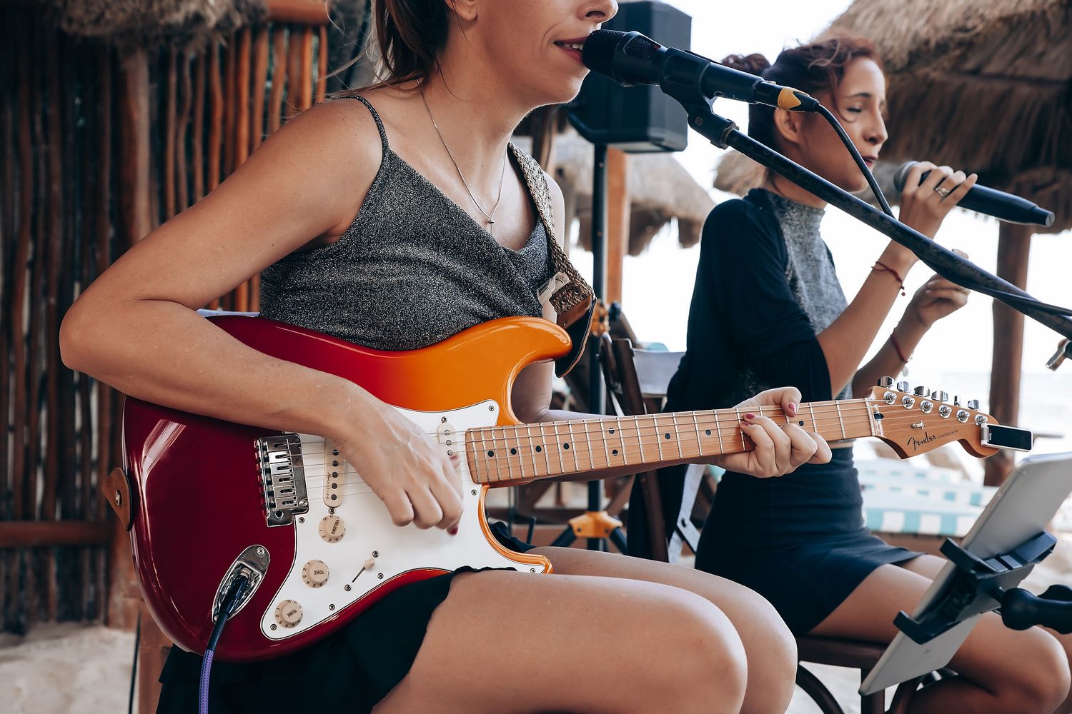 Musician playing red Stratocaster guitar during outdoor performance.