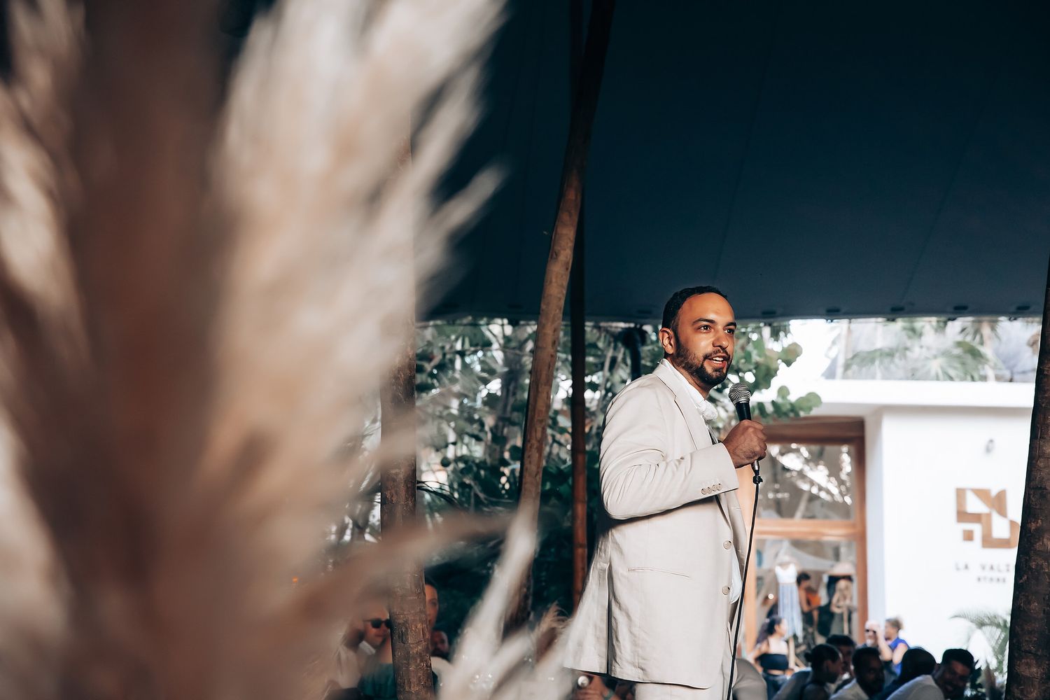 Intimate wedding moment captured through blurred tropical leaves in foreground.