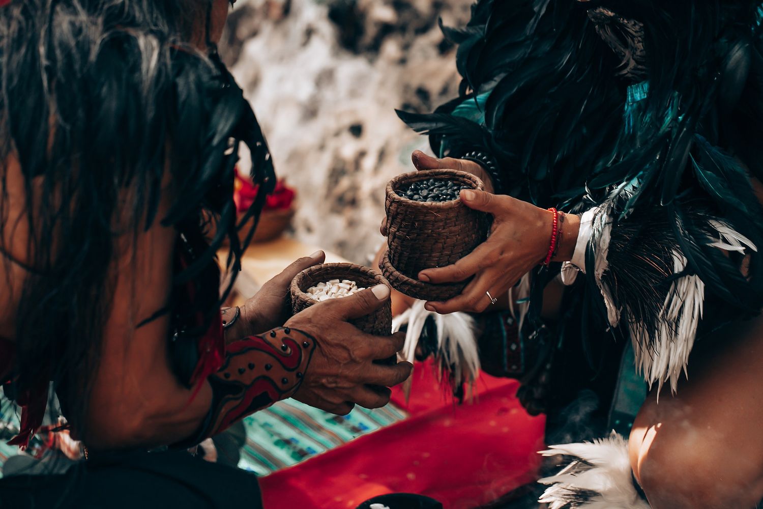 Two hands sharing a traditional ceremonial drink in clay cups during a Mayan ritual.