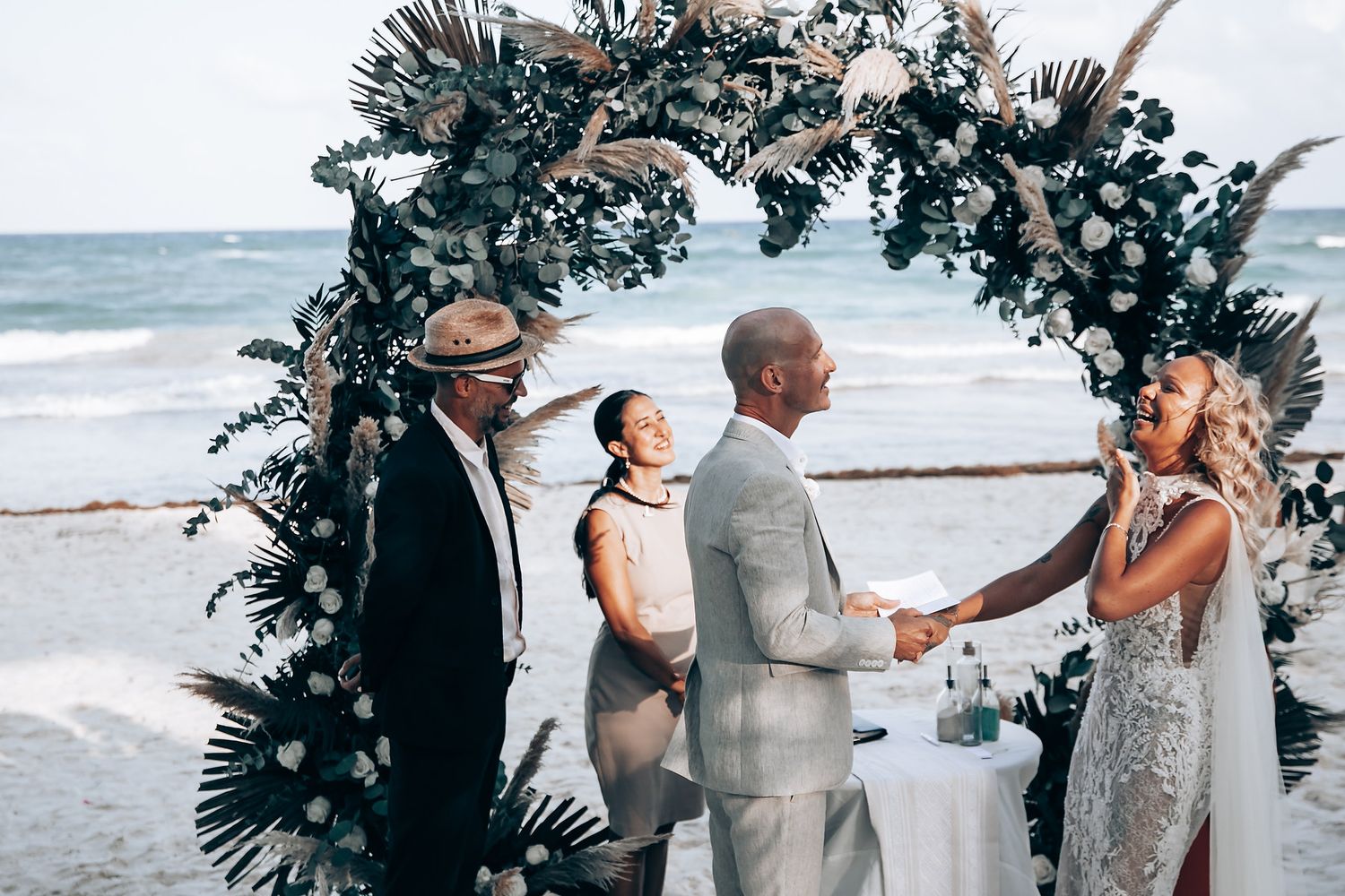 Beachside wedding ceremony setup with floral arch and ocean backdrop.