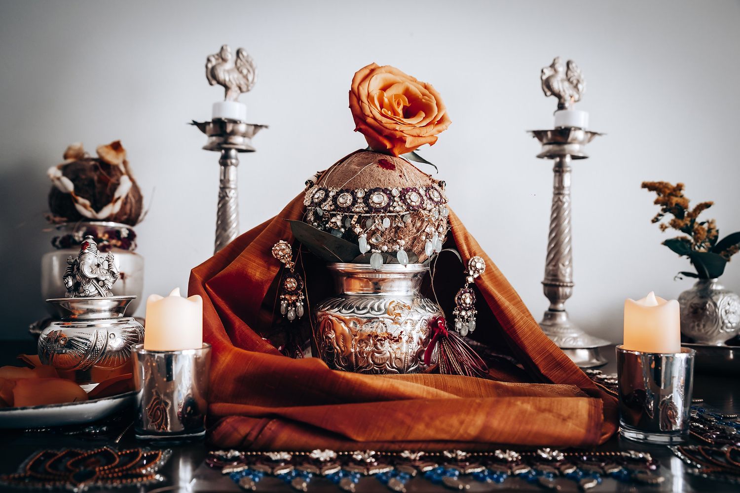 Elegant table setting with orange roses and decorative silver pieces.