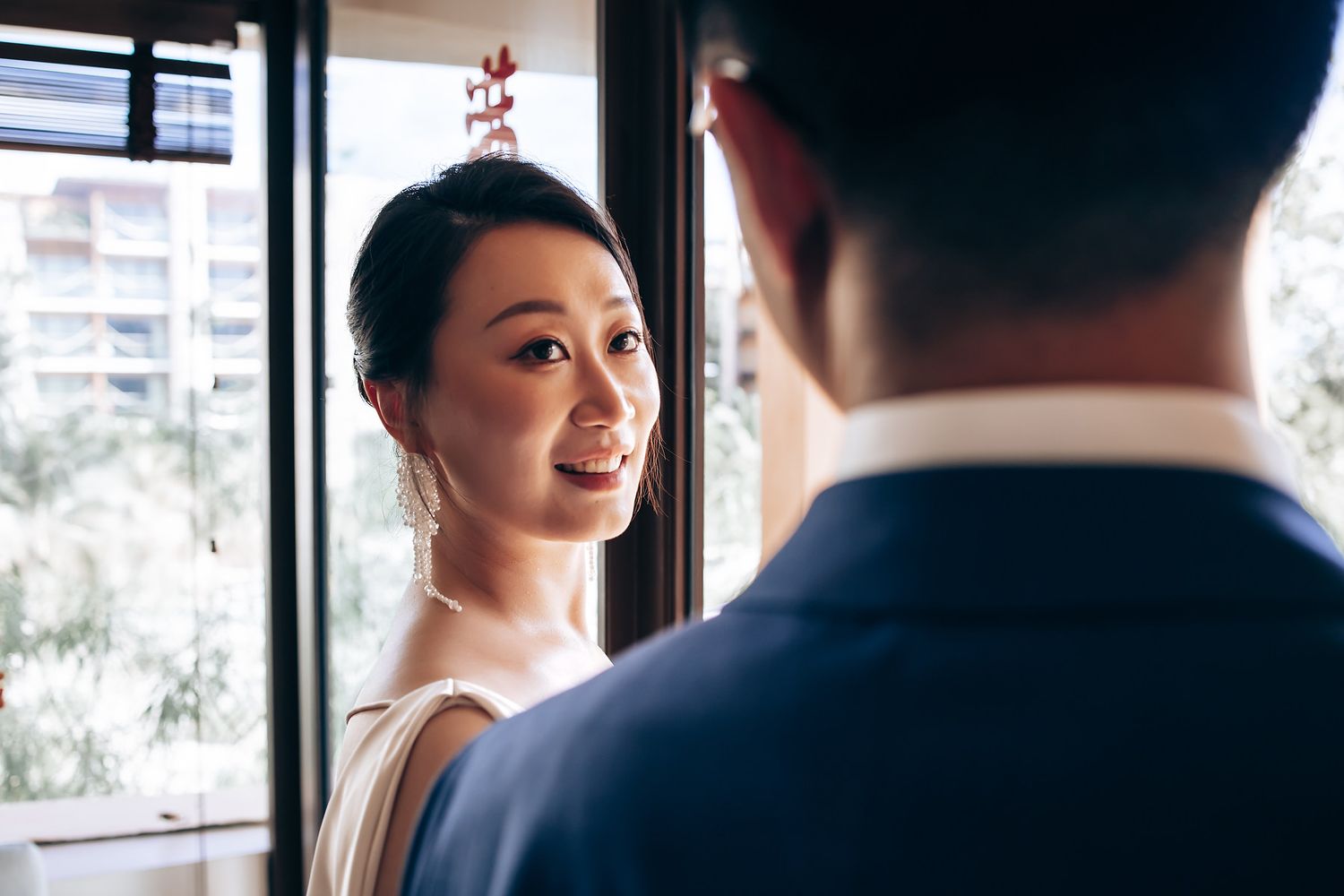 Two people having an intimate conversation by a window in natural lighting.