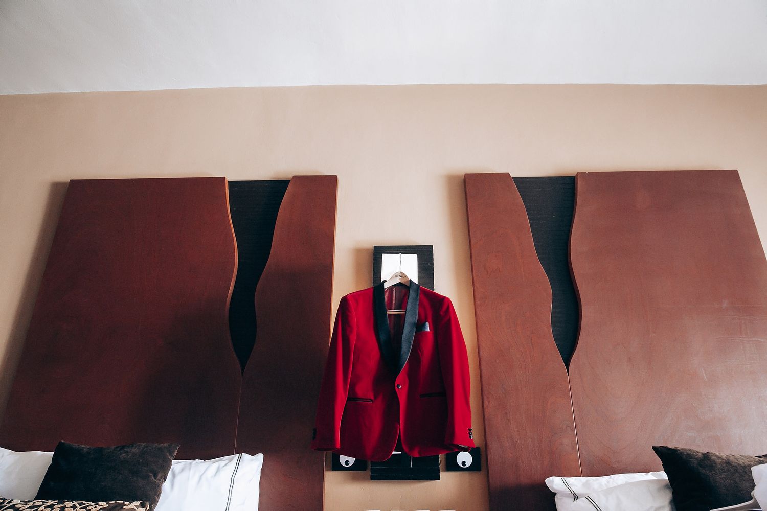 A red suit jacket hangs between two brown panels with black accents mounted on a wall.