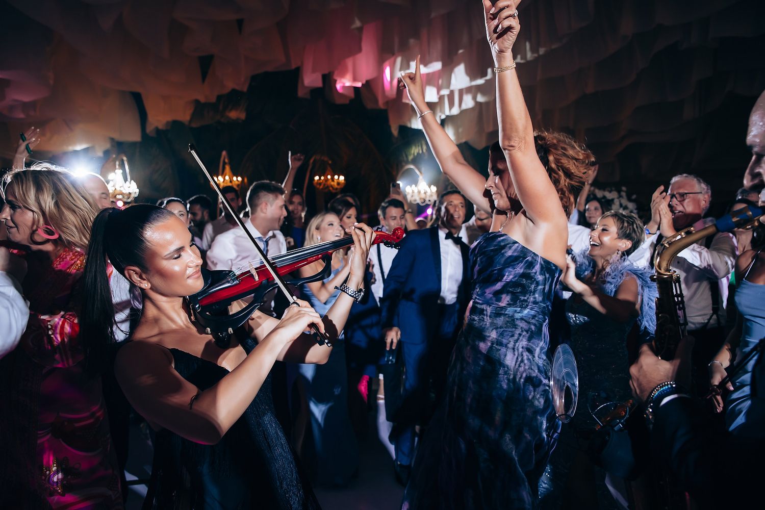 Energetic dance party at wedding reception with colorful lighting and enthusiastic guests.