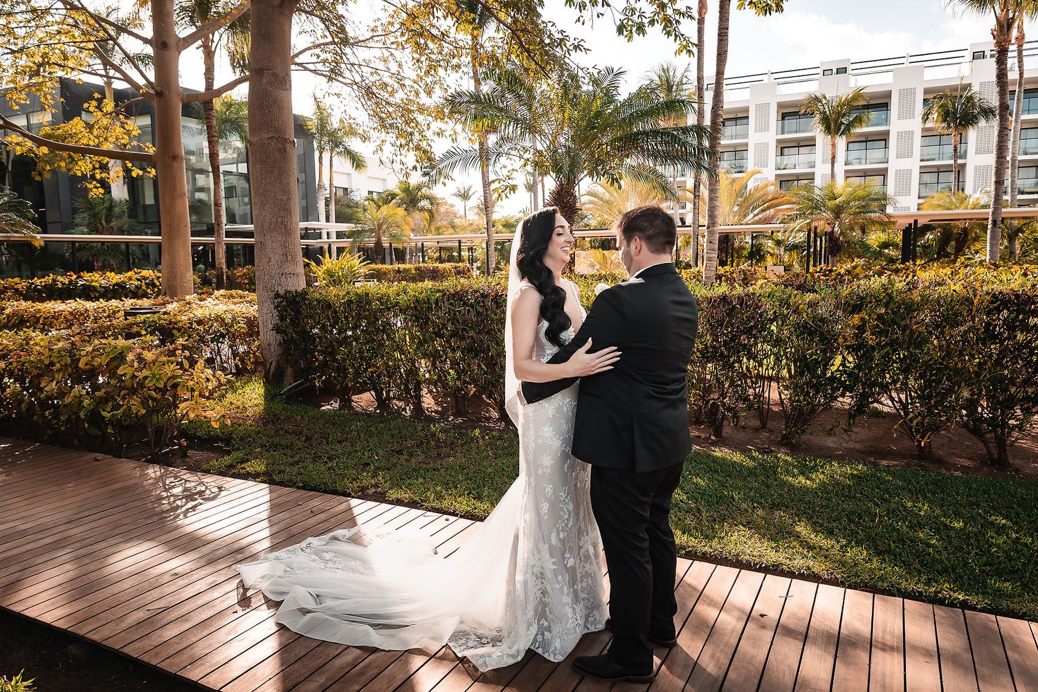 Bride and groom share an intimate moment during their first look on a tropical garden boardwalk.