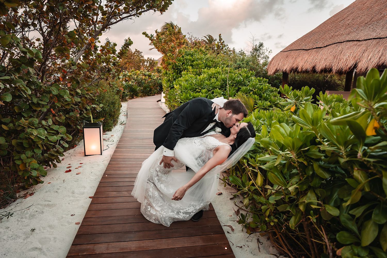 Wedding photography on a wooden boardwalk surrounded by lush tropical gardens.
