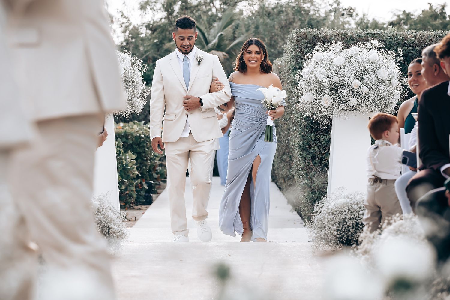 Wedding ceremony processional on white aisle with guests in light summer attire.