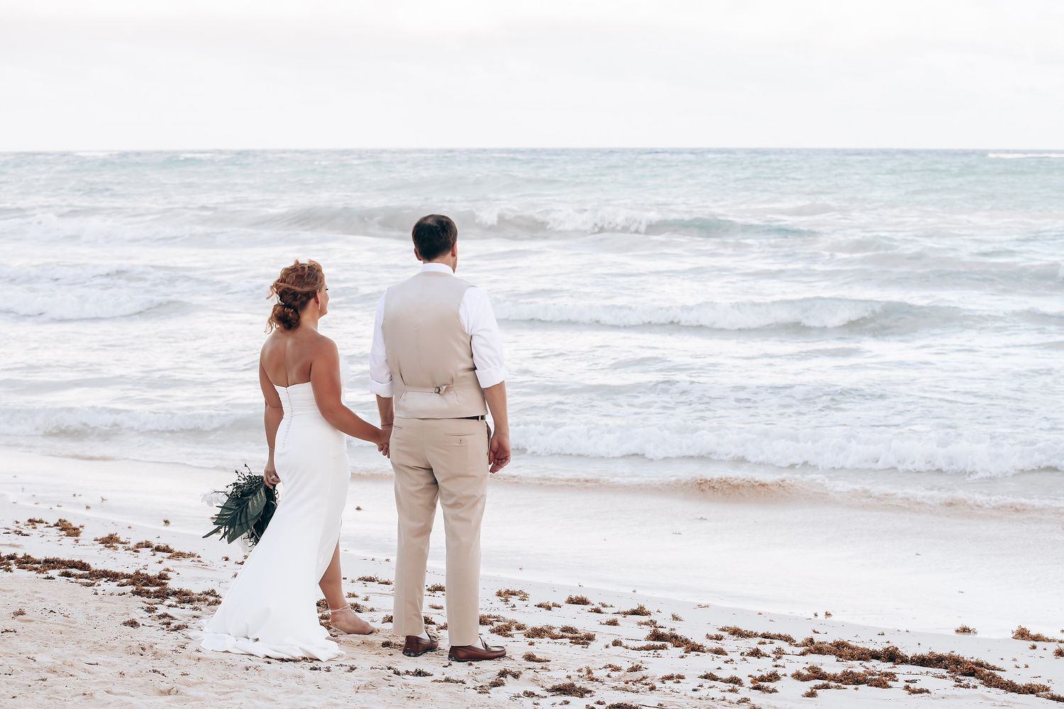 Couple walking along a peaceful beach with gentle waves in the background.
