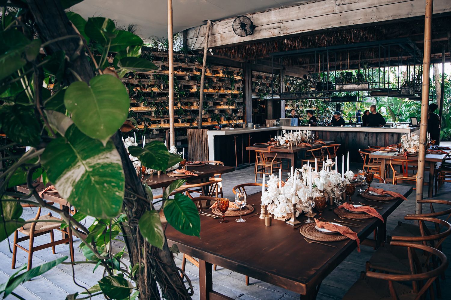 Modern restaurant interior with lush tropical plants and ambient lighting.