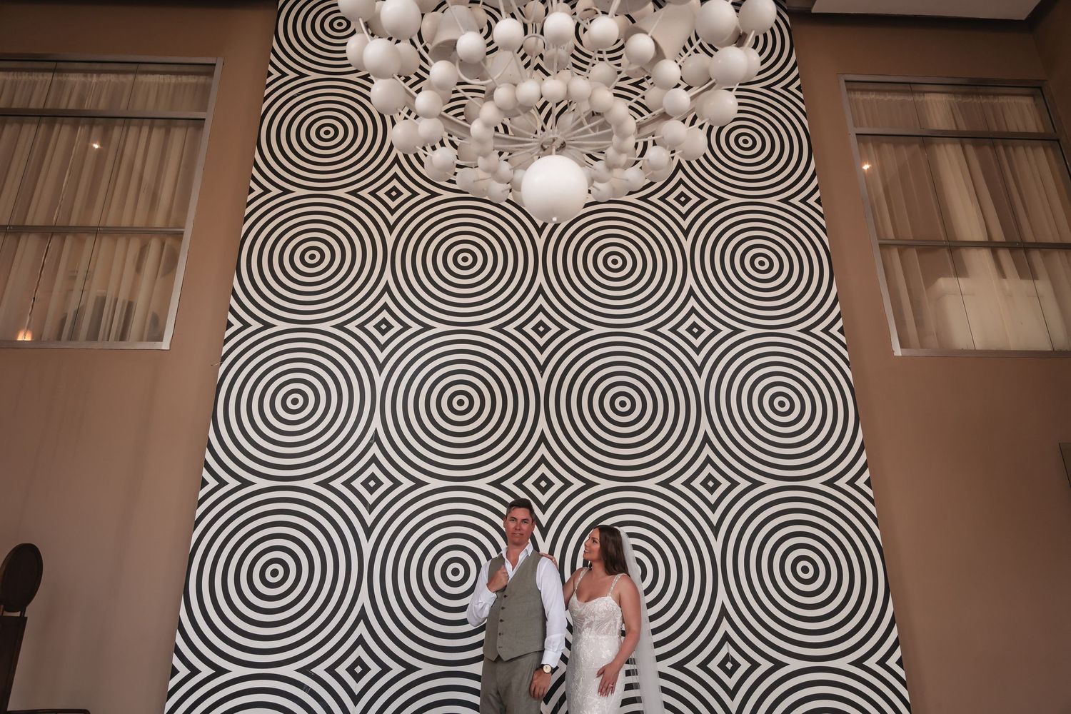 Modern wedding venue features dramatic black and white circular pattern wallpaper and pendant lighting.