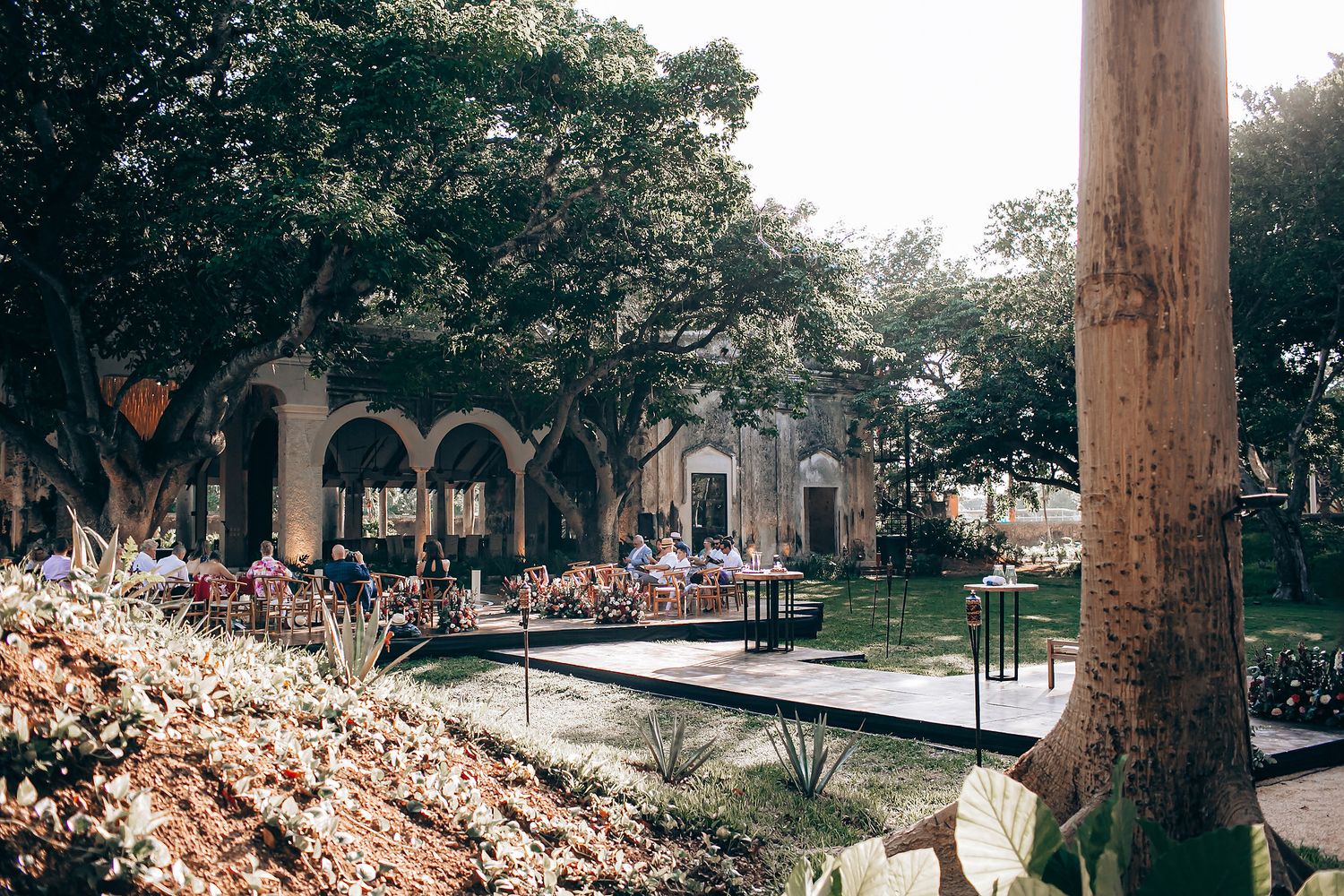 Outdoor courtyard with arched colonnade and landscaped gardens featuring tropical trees and plants.
