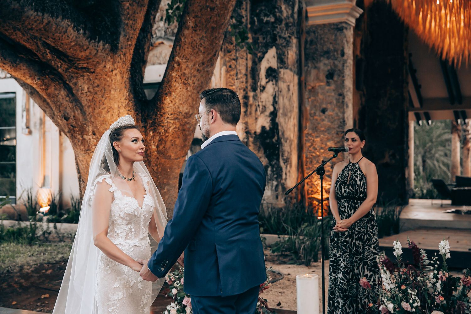 Romantic wedding couple shares intimate moments in a garden setting illuminated by warm string lights and natural foliage.