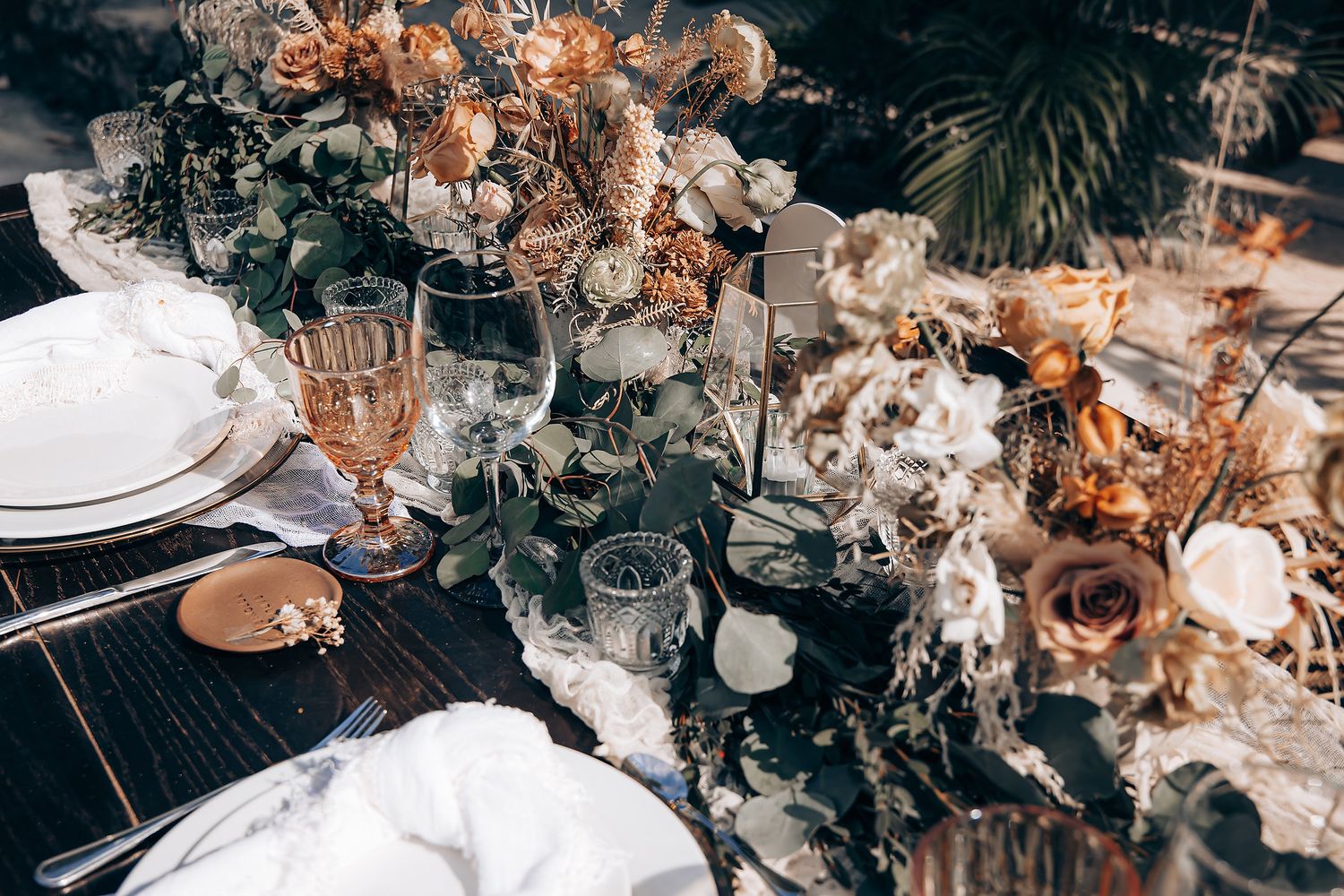 Elegant wedding reception table setting with warm lighting, floral arrangements, and crystal glassware in rustic style.