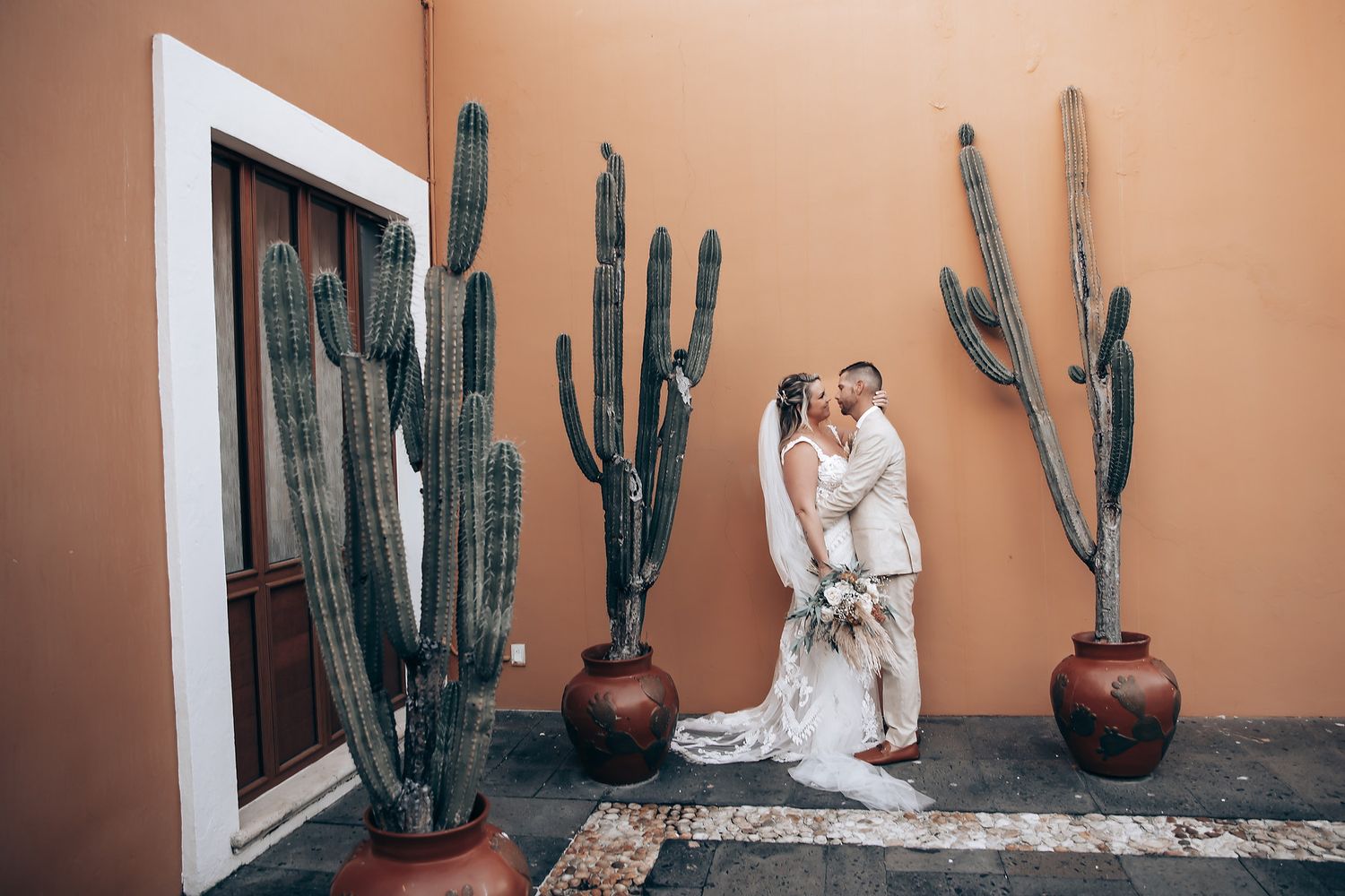 Desert-themed wedding setting with tall cacti and terracotta walls creating a southwestern ambiance.