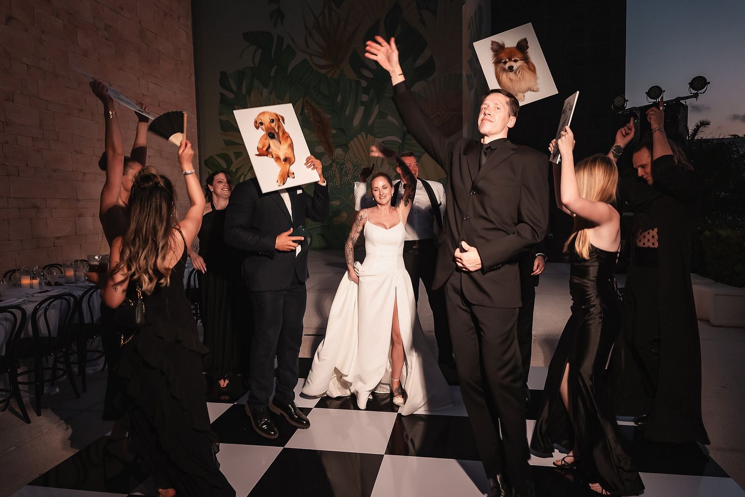 Wedding reception dance floor filled with guests celebrating under dim lighting.
