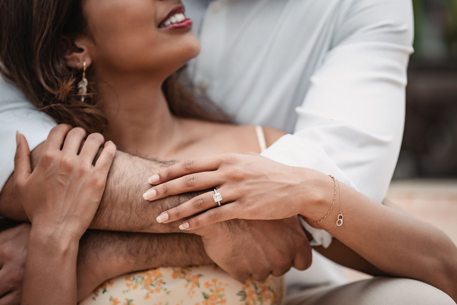 Close-up of couple's hands during intimate moment wearing white and peach outfits.