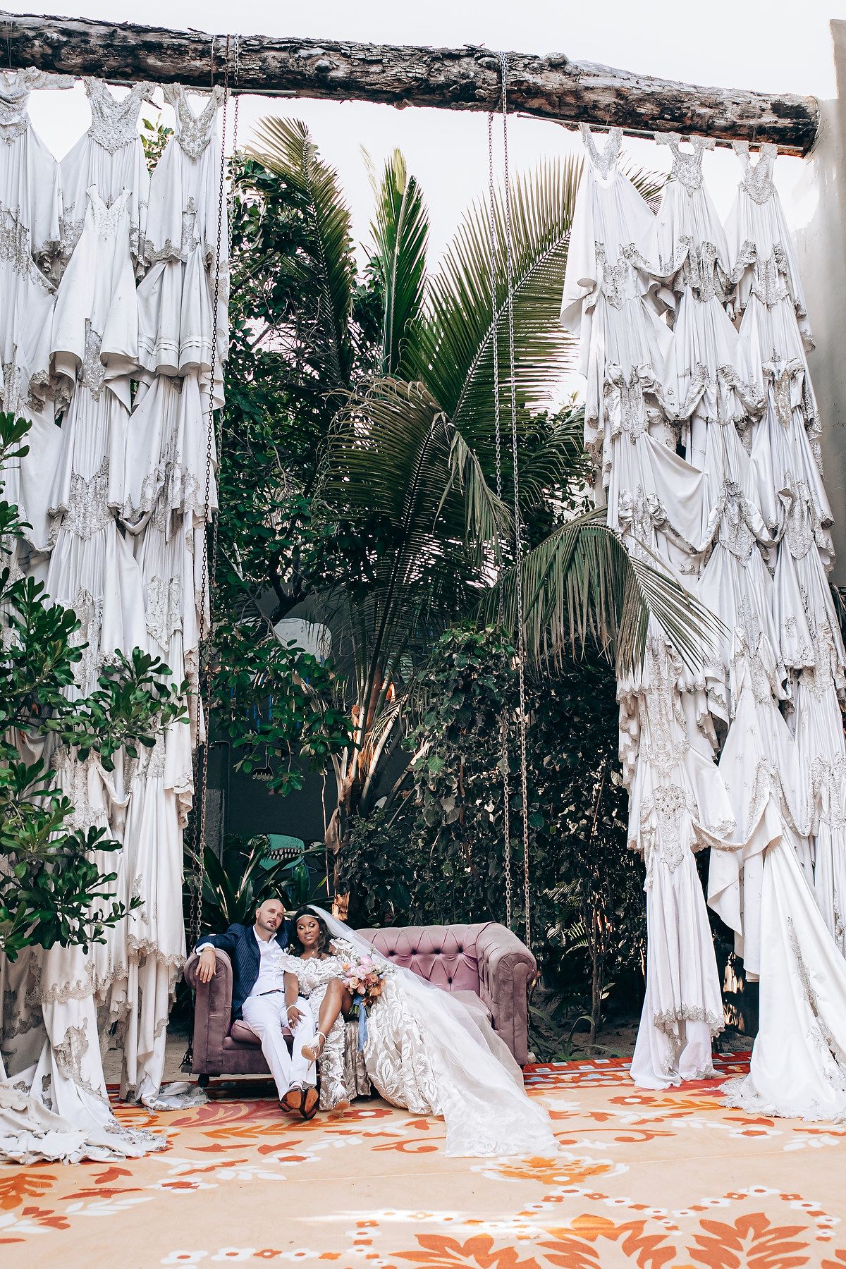 White draped fabric backdrop with vintage furniture creates a romantic outdoor lounge setting.