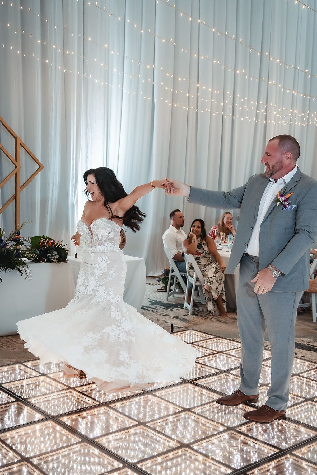 Bride and groom share their first dance on a glowing LED dance floor at a elegant wedding reception.