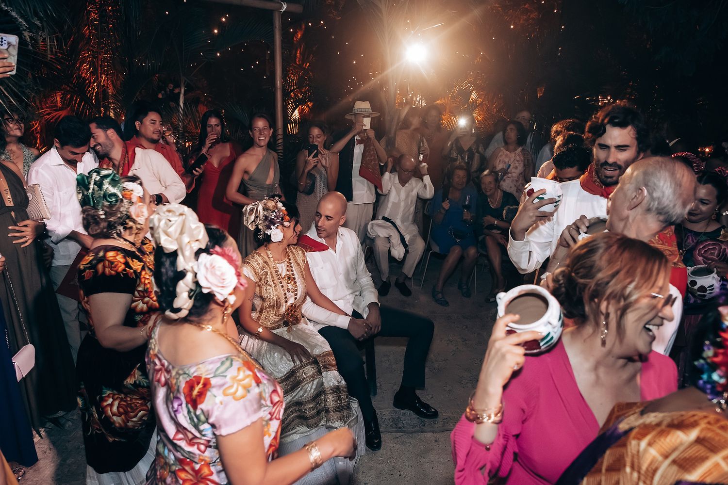 Couples dancing together at a dimly lit wedding reception with dramatic lighting and a festive atmosphere.