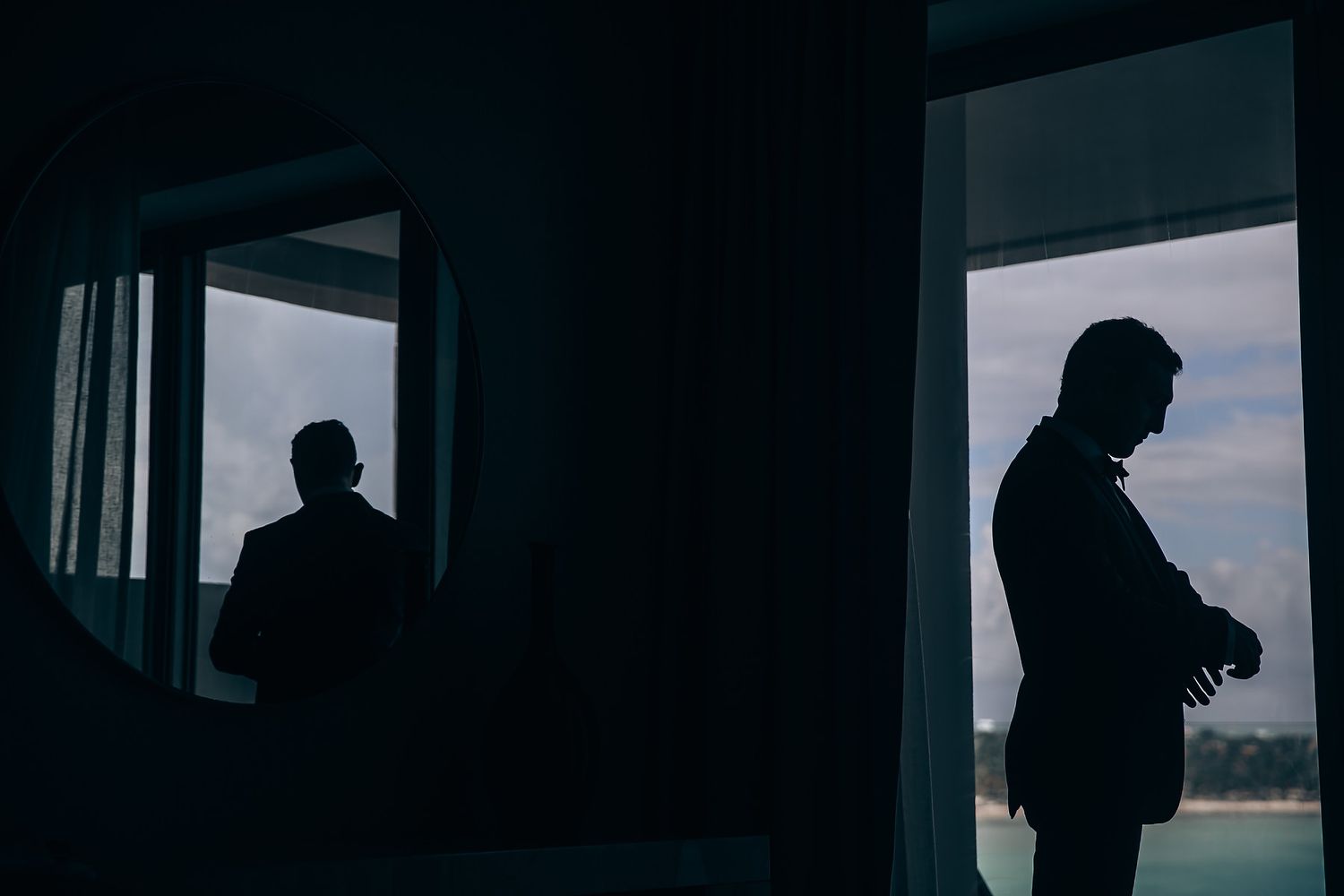 Silhouettes of wedding guests against a bright window backdrop.
