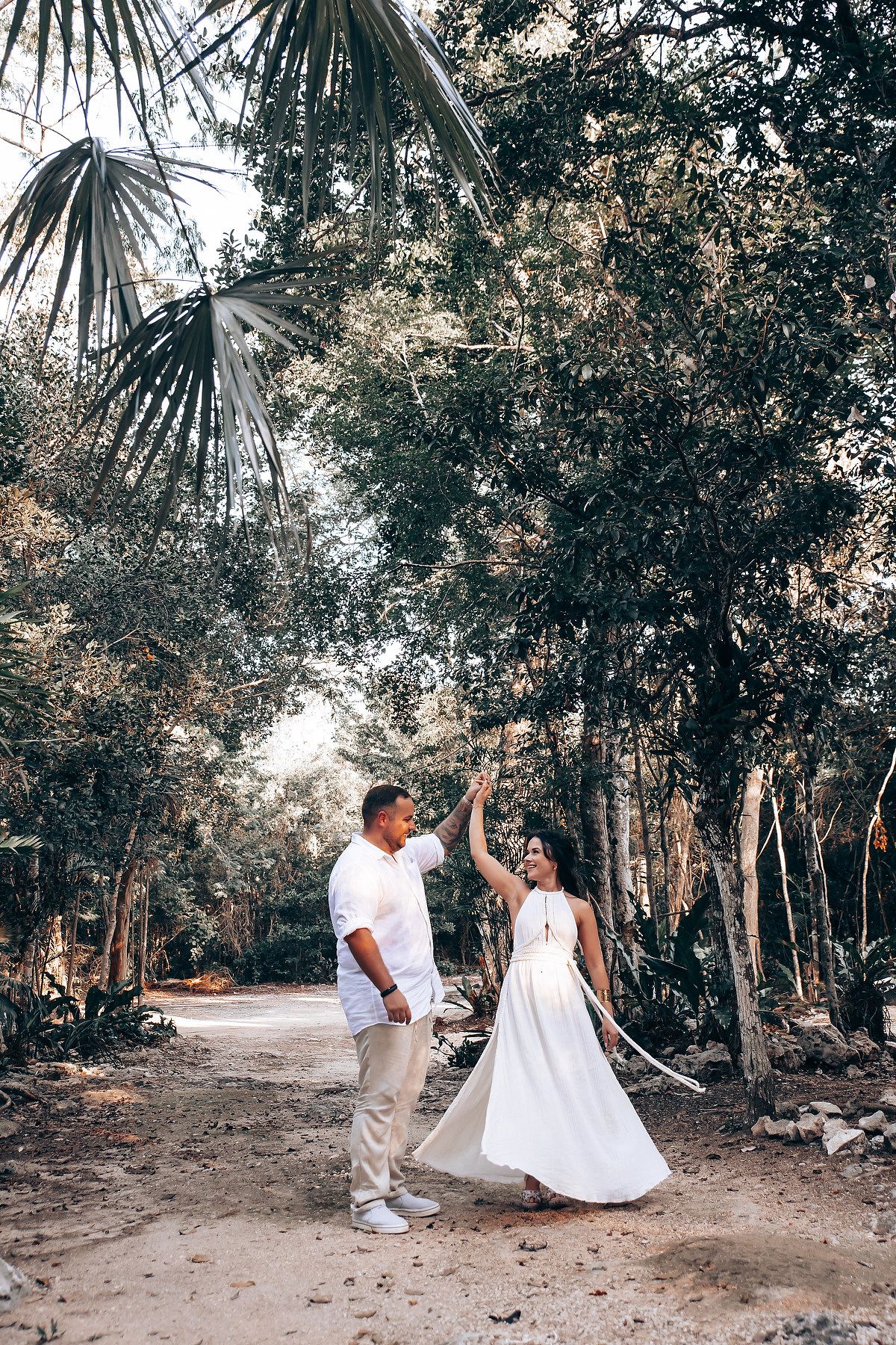 Joyful dance moment on tropical forest path with palm trees overhead.
