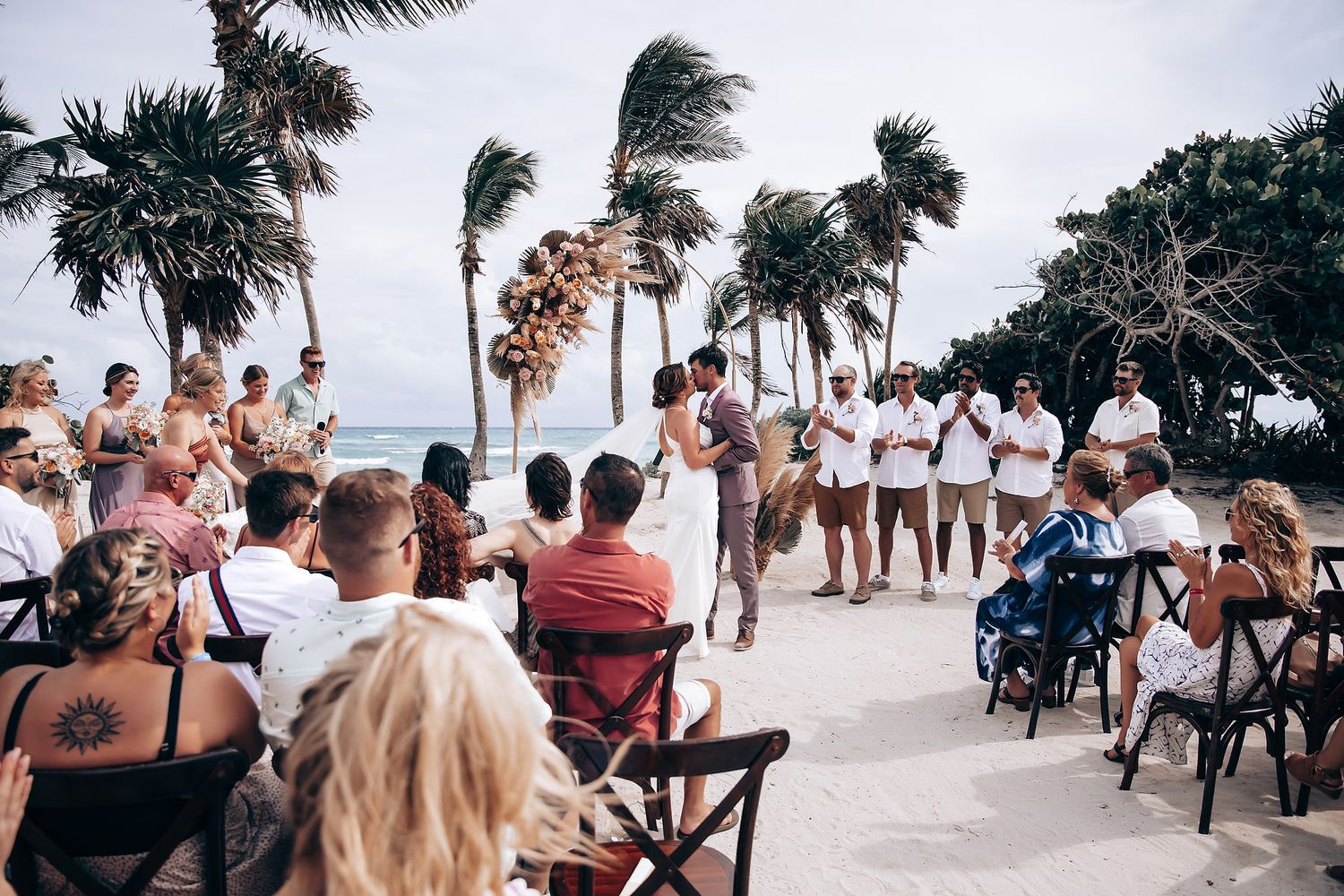 Palm trees sway in the wind at a tropical beach wedding ceremony setup.