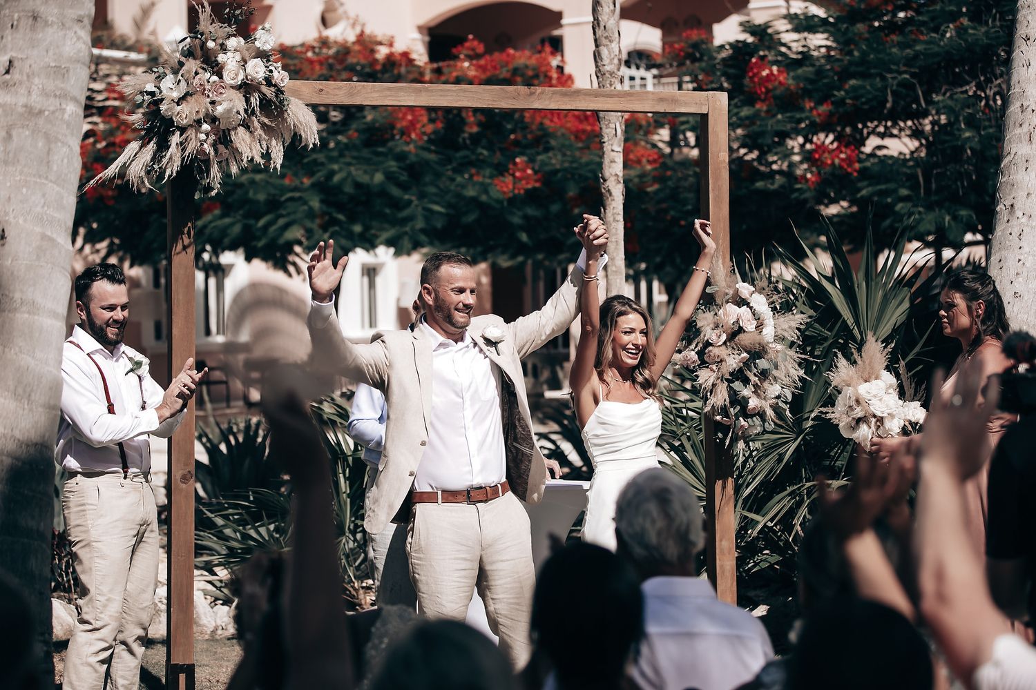 A bride and groom walk together surrounded by wedding guests.