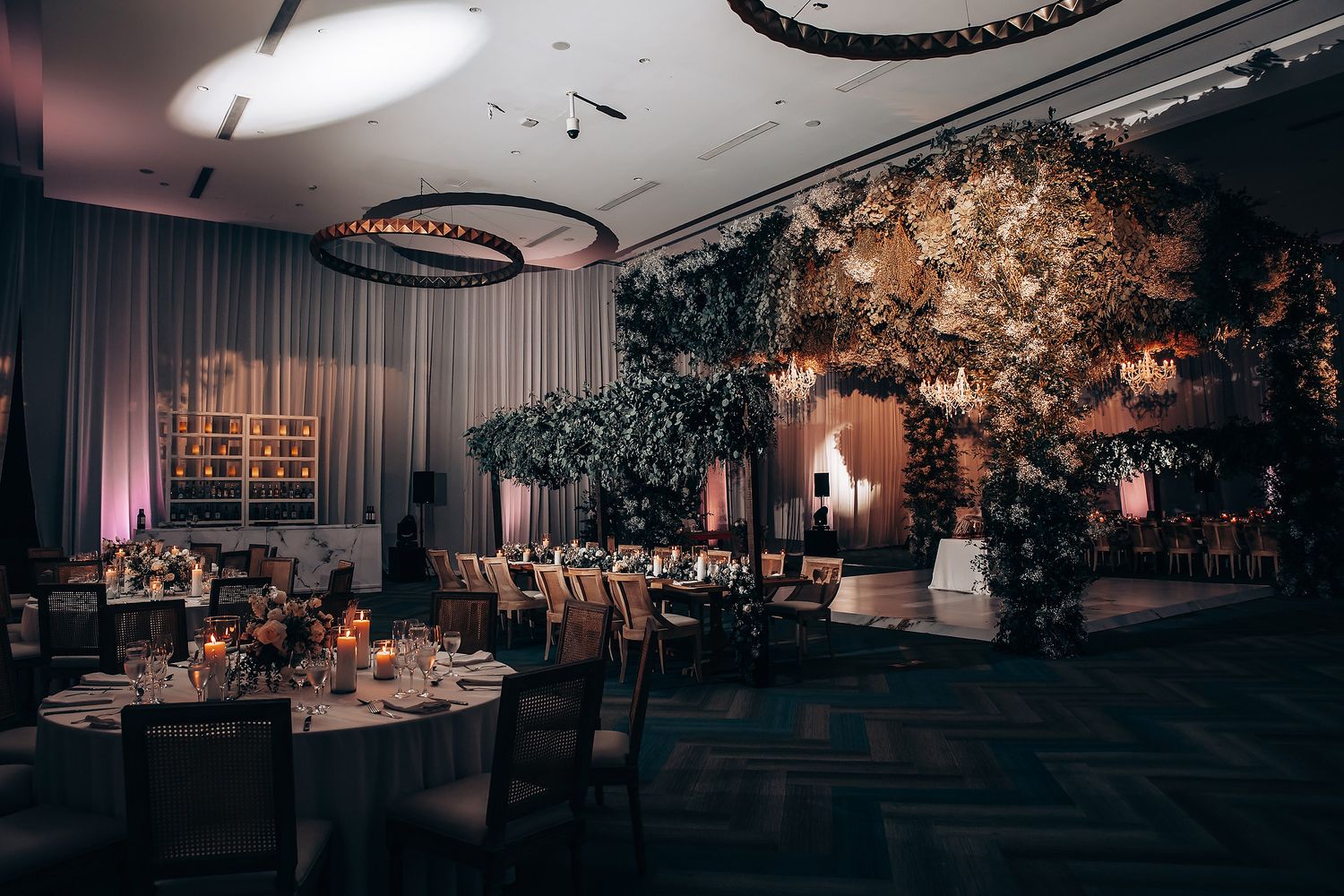 Elegant wedding reception venue with floral decor, chandeliers, and romantic mood lighting.