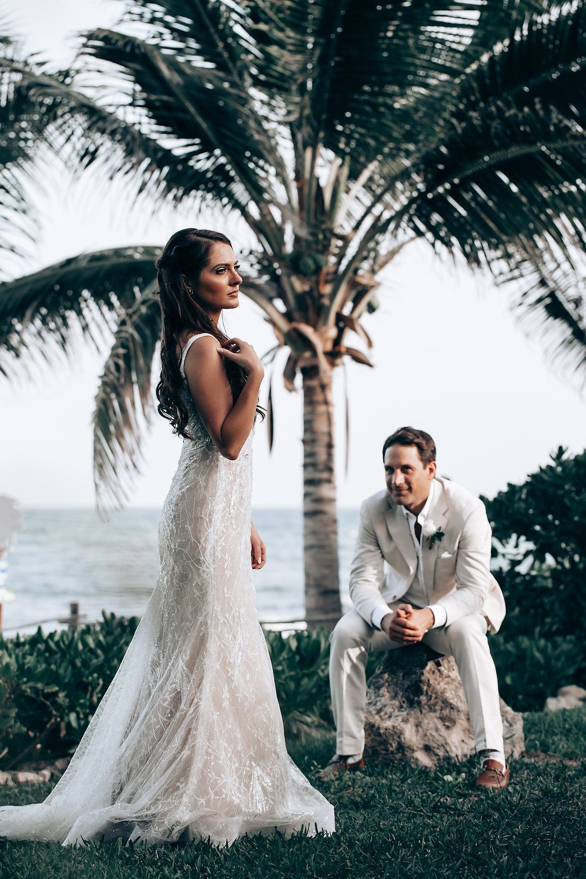 Tropical beach wedding portrait with palm trees and ocean backdrop.