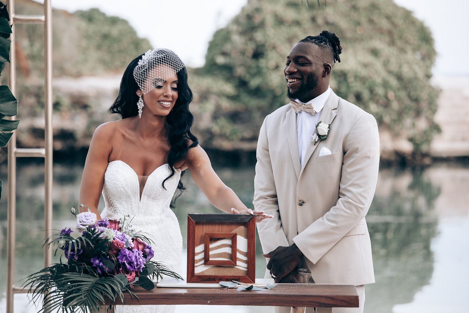 A couple stands at a wooden altar during their waterfront wedding ceremony.