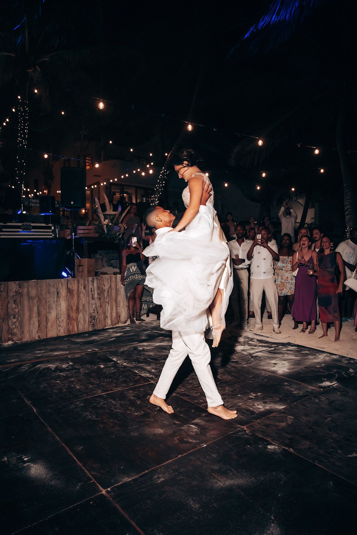 Wedding couple performs dramatic dance moves under romantic evening lighting at outdoor reception.